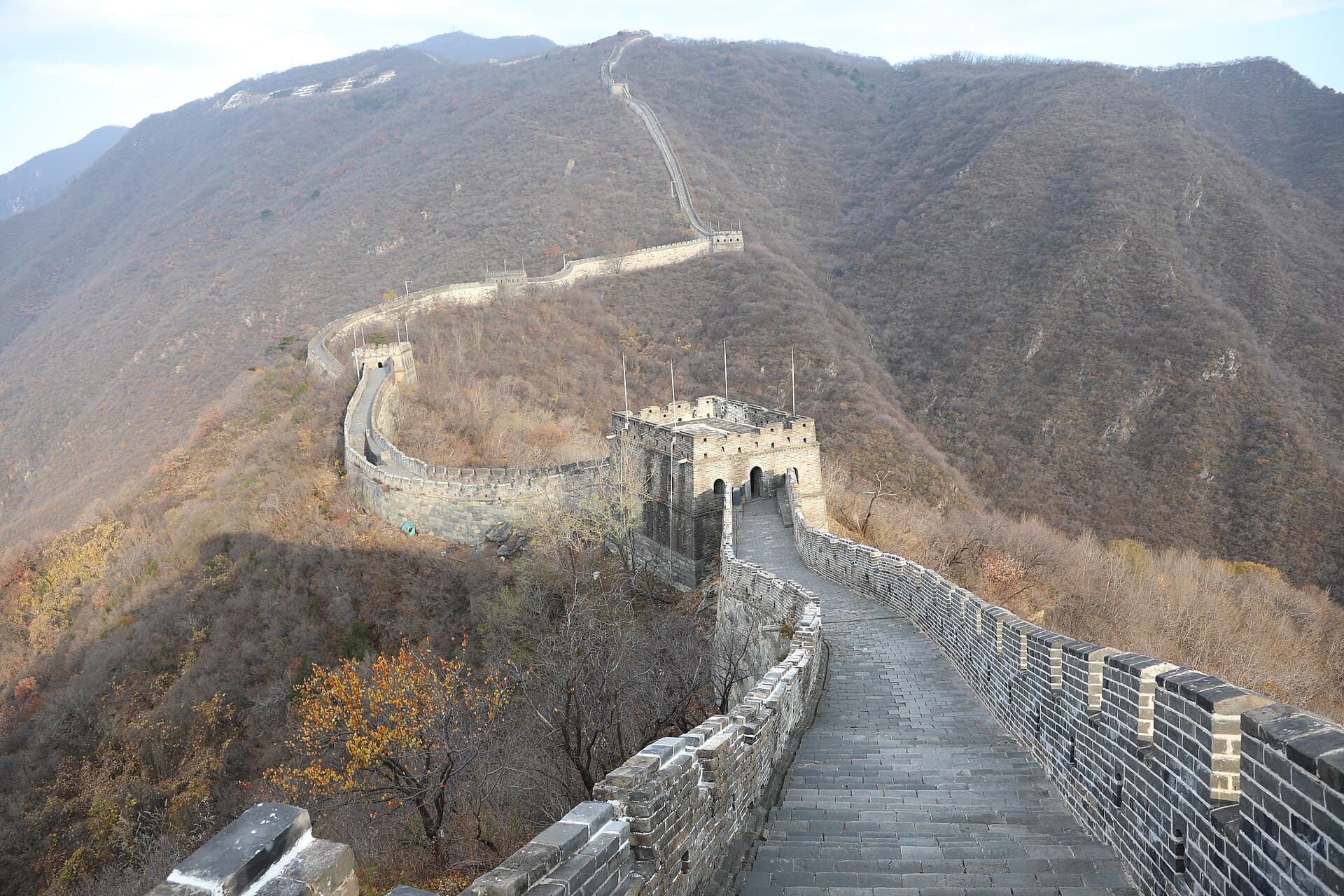The Great Wall at Mutianyu climbing along a wooded ridge in autumn, with watchtowers along the way