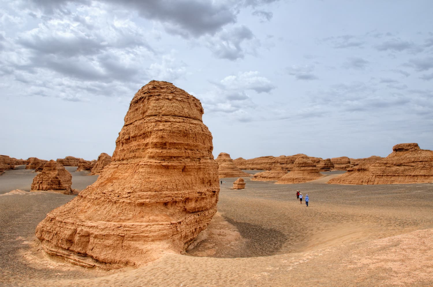 A tall layered clay formation carved by wind, standing on flat desert at Yadan National Geopark