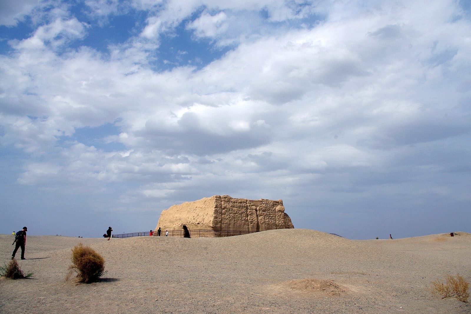 The square mud-brick fort of Yumen Pass standing alone in flat desert under a cloudy sky