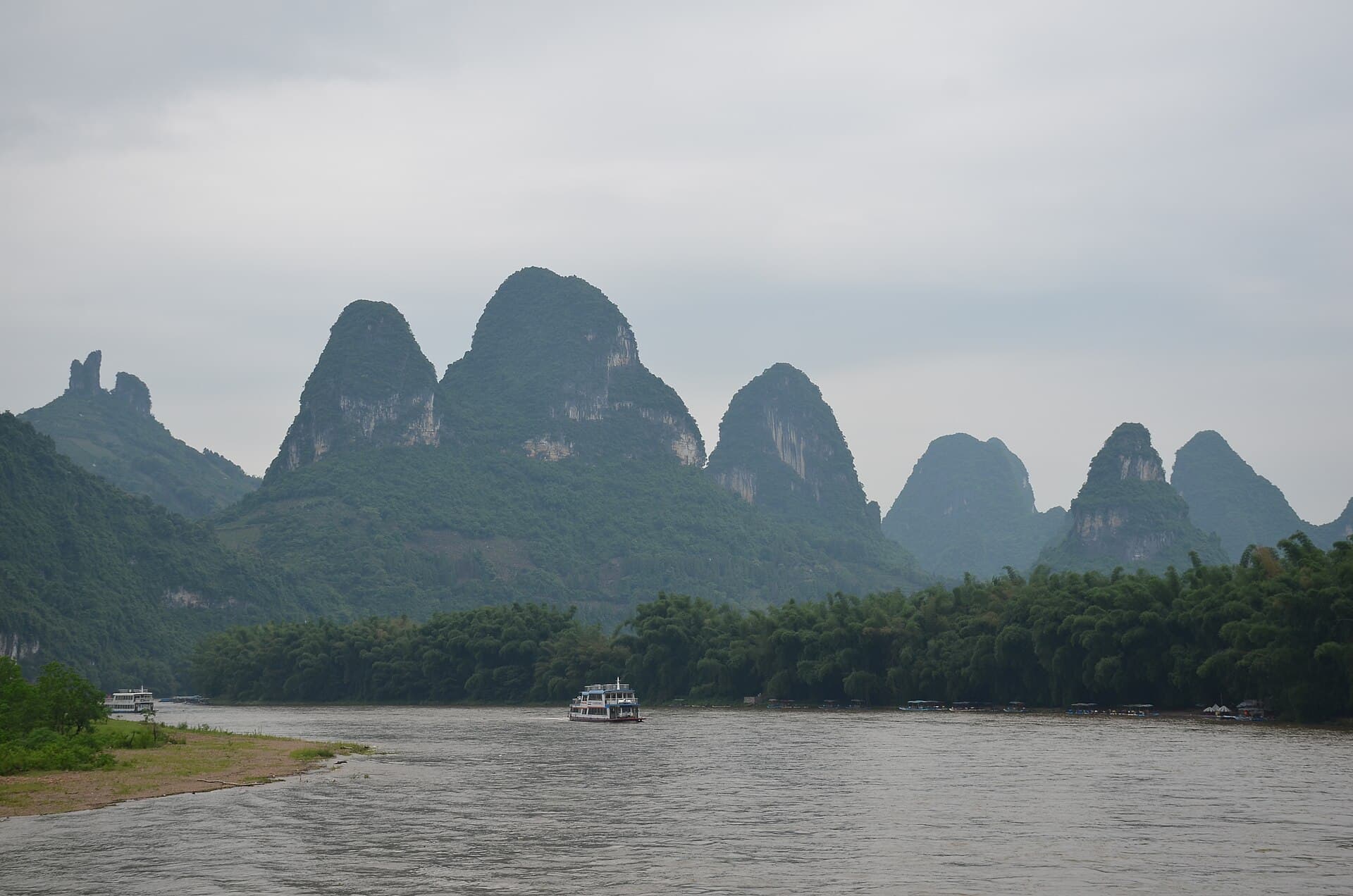 The Li River curving between steep green karst hills, with a cruise boat on the water