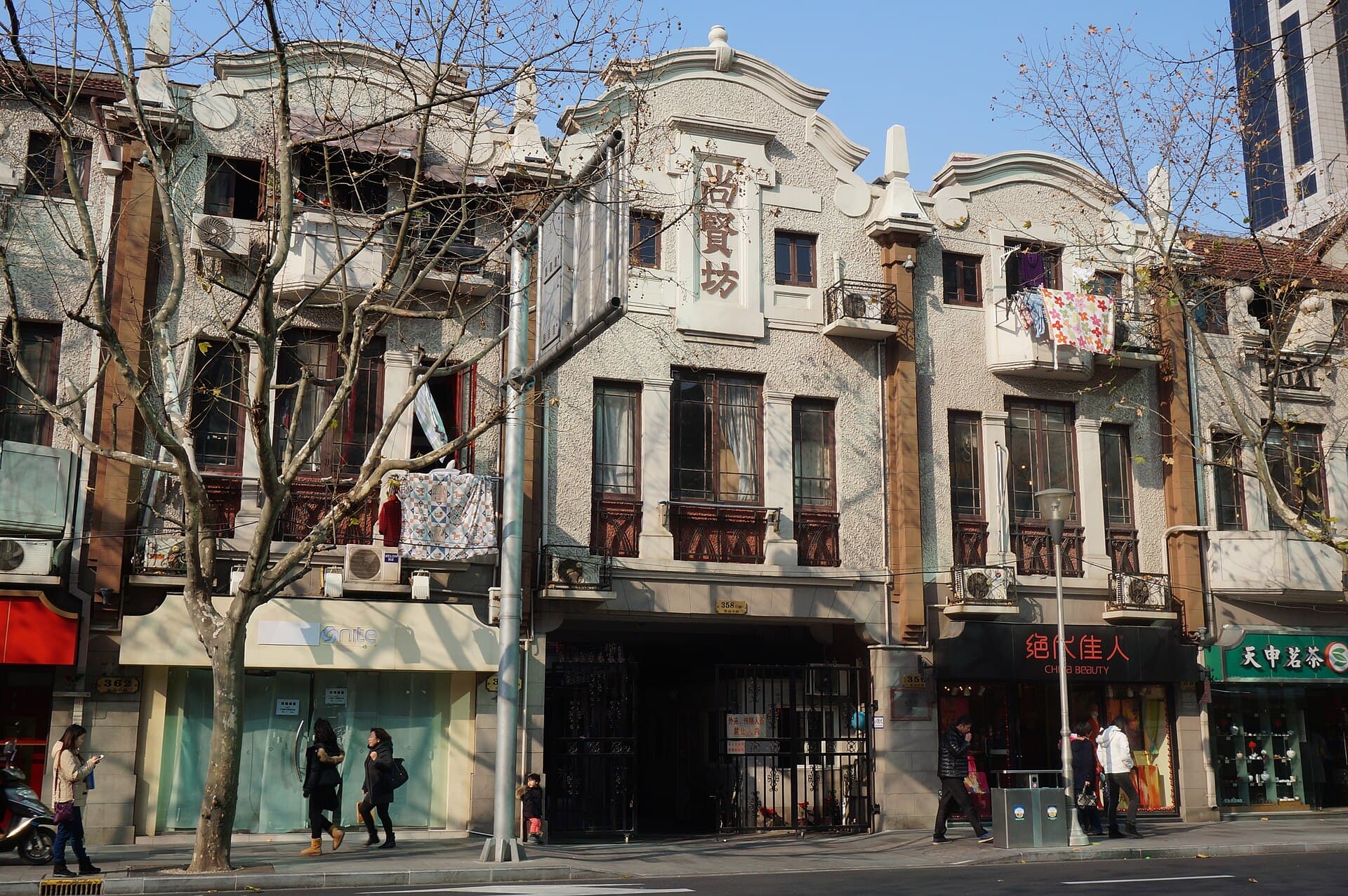 A row of two-storey brick shikumen lane houses in Shanghai with carved stone gateways and shopfronts below