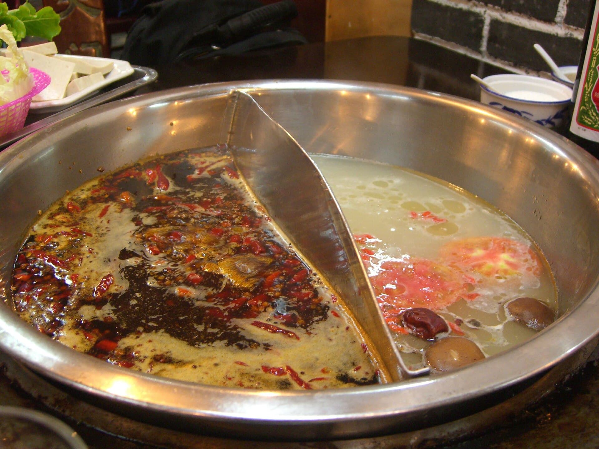 A divided hotpot with red chilli broth on one side and clear broth on the other