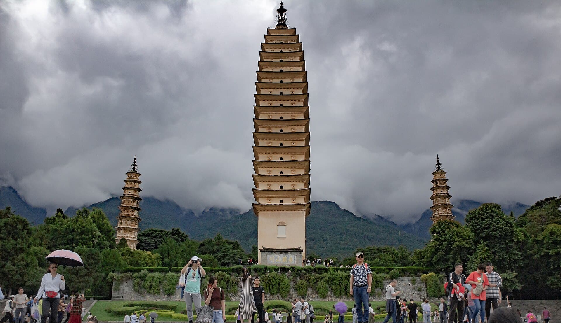 The tall square Qianxun Pagoda flanked by two smaller octagonal pagodas, with cloud on Cangshan behind