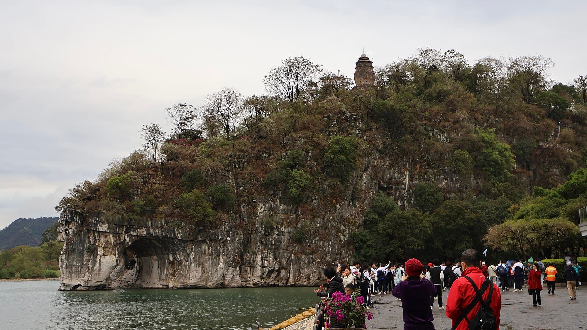 Elephant Trunk Hill, a limestone hill with a natural arch at the water's edge like an elephant drinking, with visitors on the path