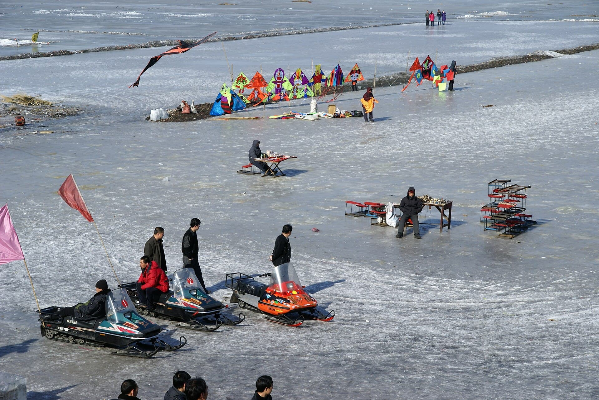 People walking and riding sledges on the frozen surface of the Songhua River in Harbin